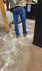 A man is standing on a dirty floor with a yellow cord.