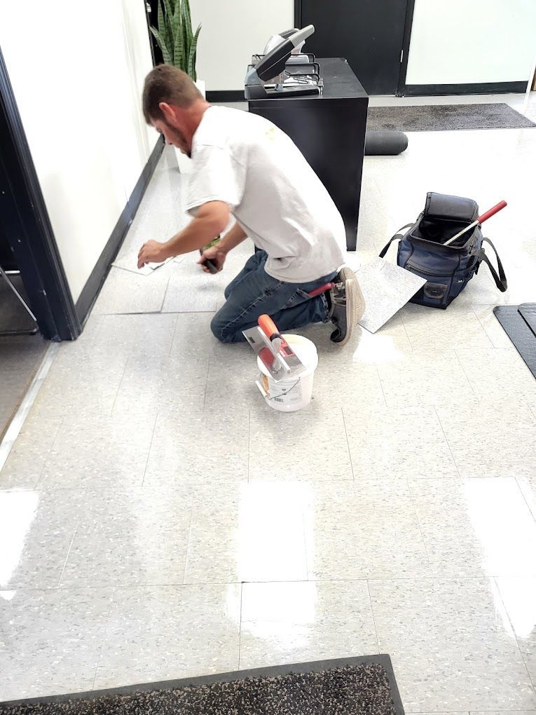 A man is kneeling on the floor in a room with tools.
