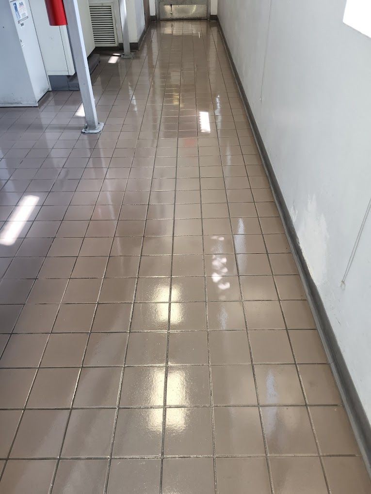 A hallway with a tiled floor and a fire extinguisher on the wall.