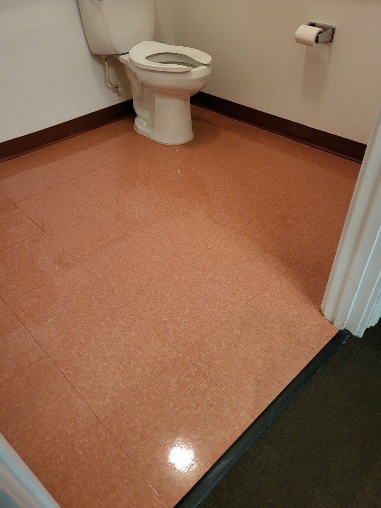 A toilet is sitting on a tiled floor in a bathroom.