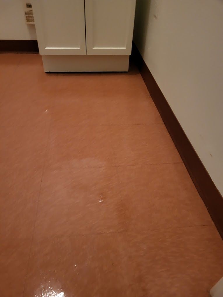 A brown floor with a white cabinet in the background.