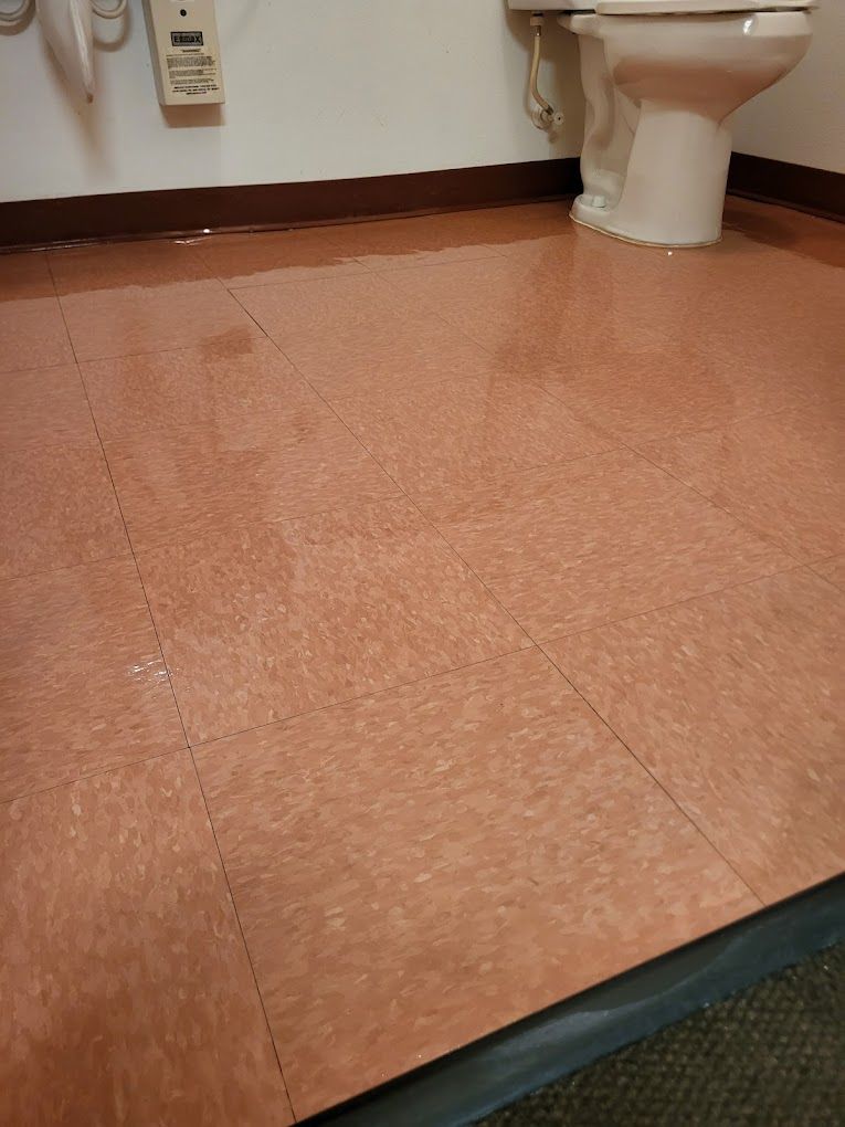A toilet is sitting on a tiled floor in a bathroom.