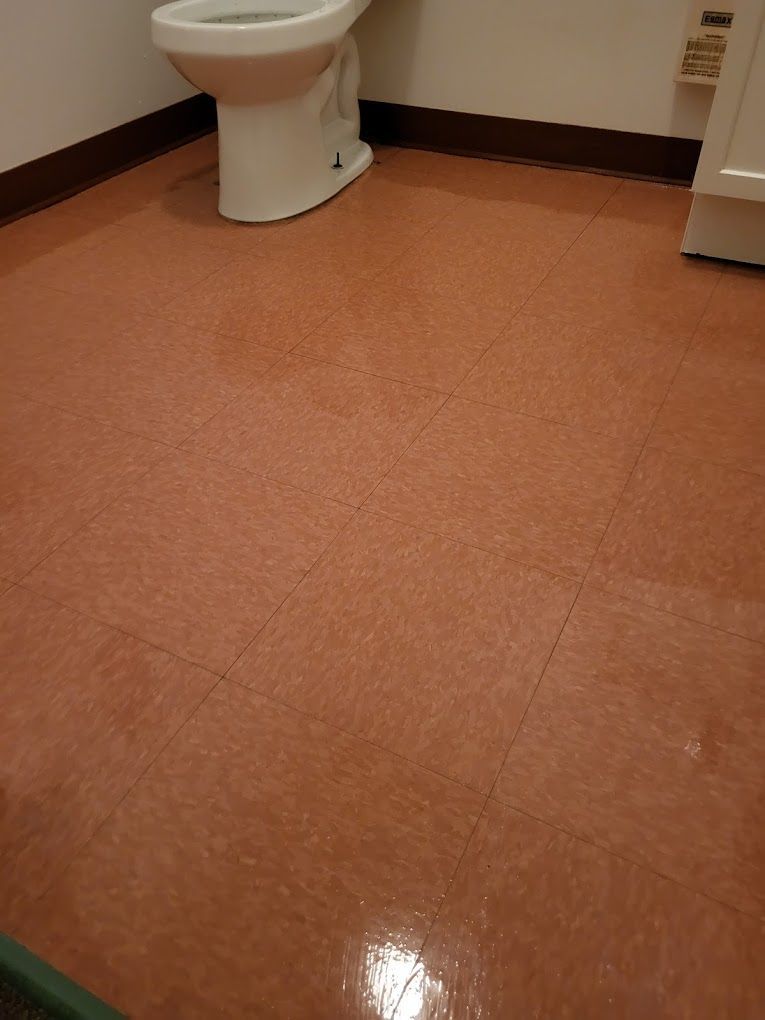 A toilet is sitting on a tiled floor in a bathroom.