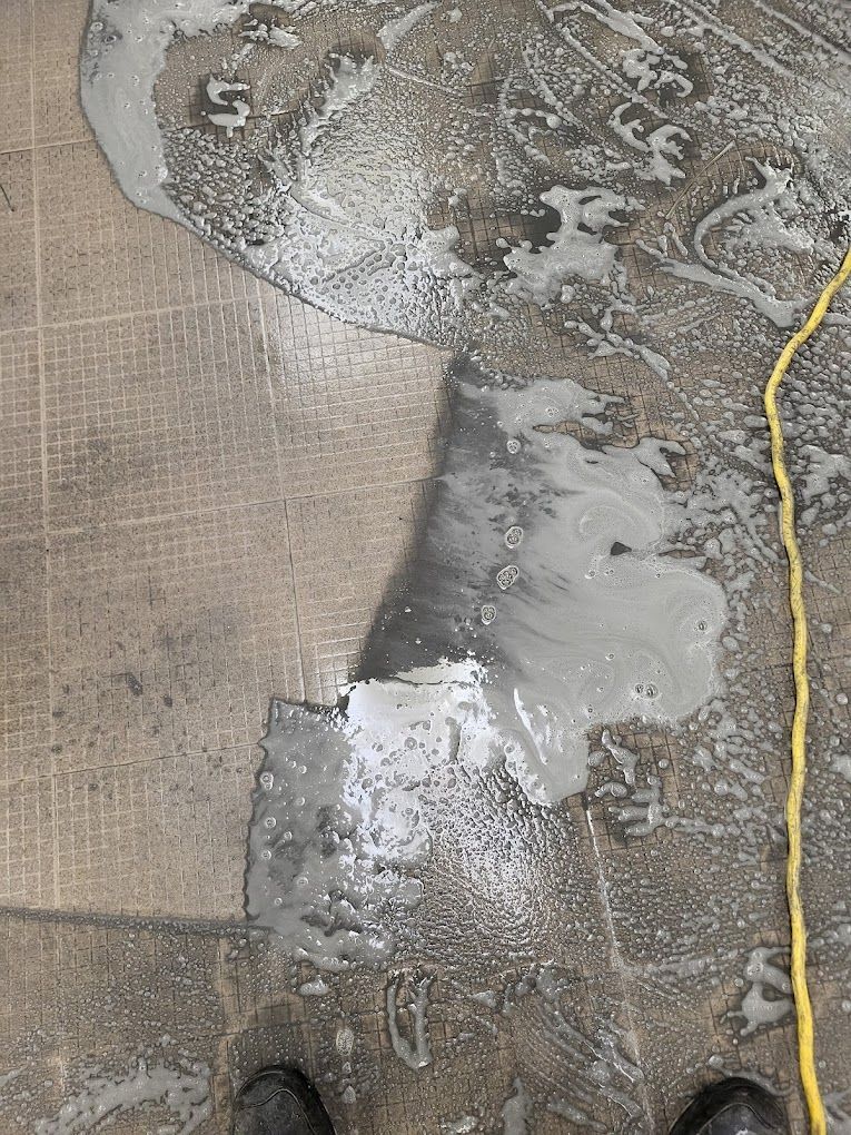 A person is standing on a dirty floor next to a yellow power cord.