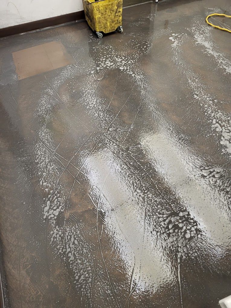 A room with a dirty floor and a yellow bucket on the floor.