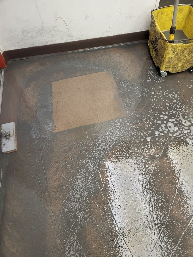 A wet floor with a mop and bucket on it