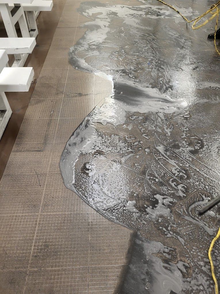 A person is cleaning the floor of a restaurant with a vacuum cleaner.