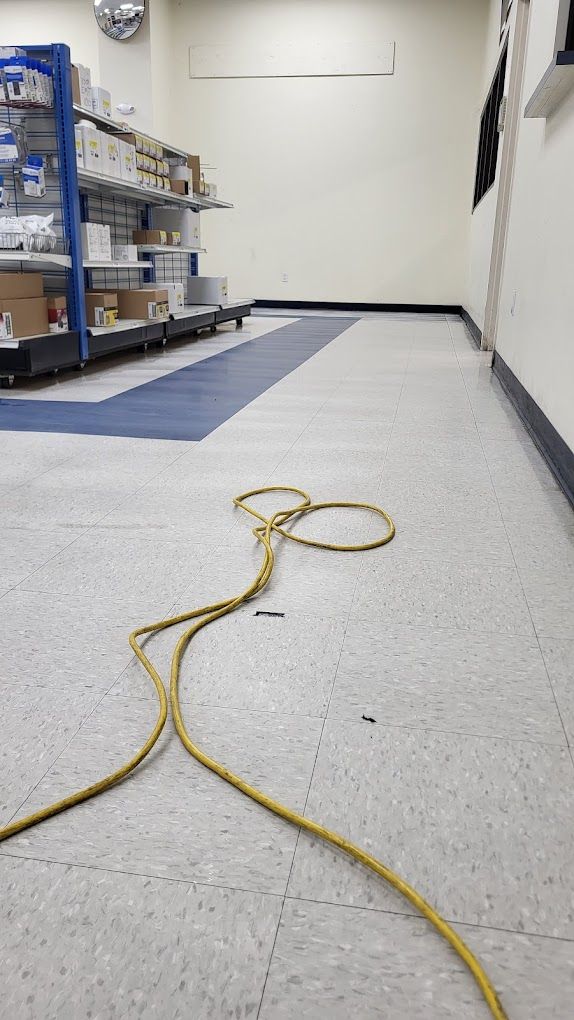 A yellow power cord is laying on the floor of a store.