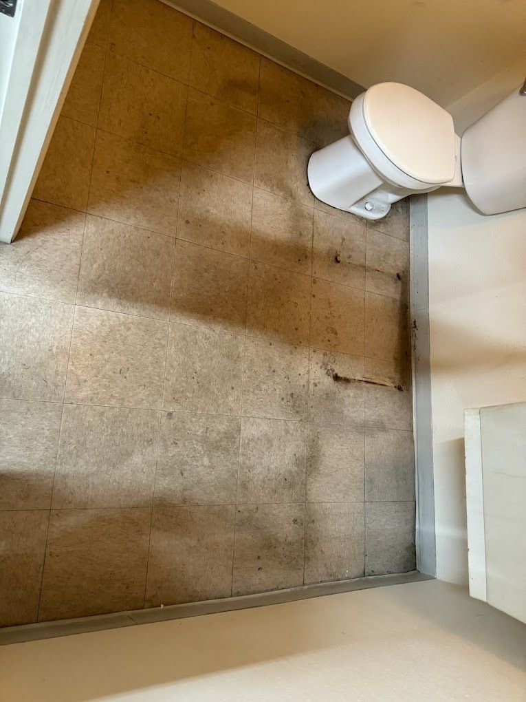 A toilet is sitting on the floor of a bathroom next to a door.