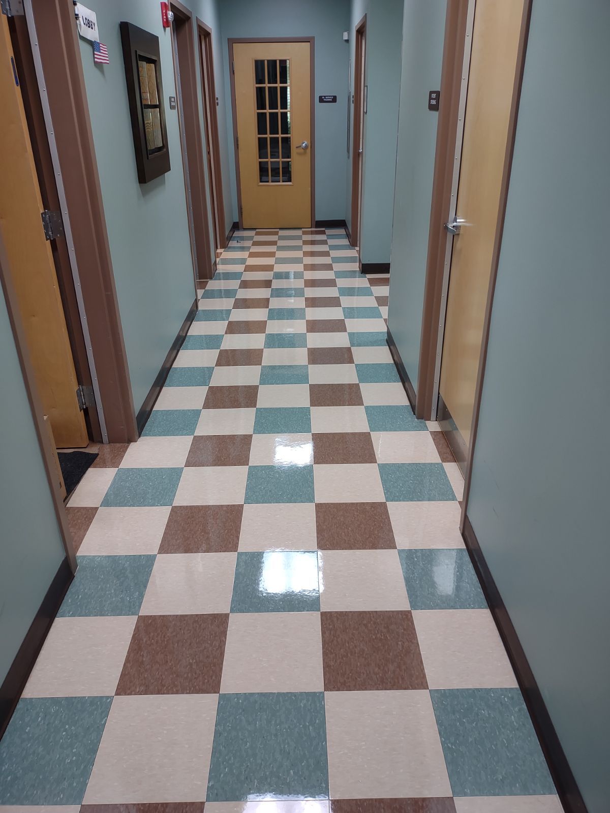 A hallway with a checkered floor and a door