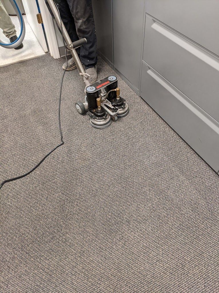 A person is cleaning a carpet with a vacuum cleaner.