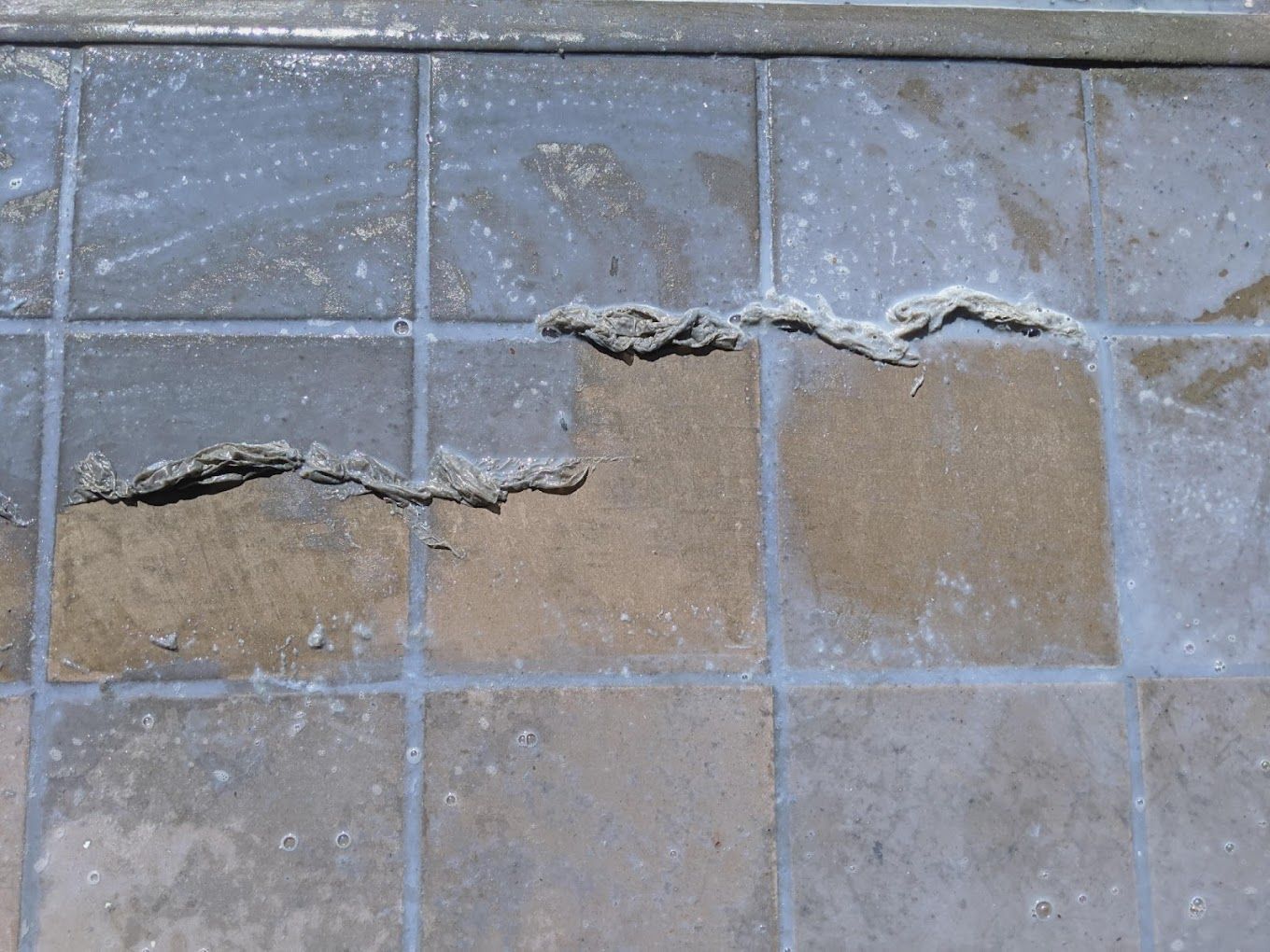A close up of a tiled floor with a few cracks in it