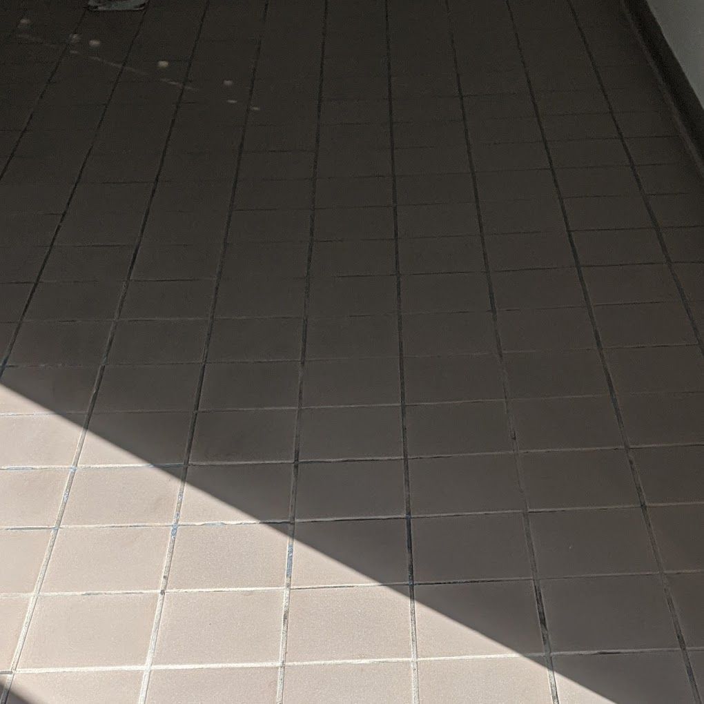 A shadow of a person is cast on a tiled floor.
