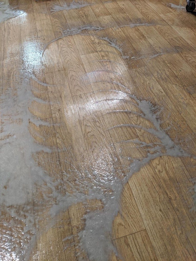 A close up of a wooden floor with water coming out of it.