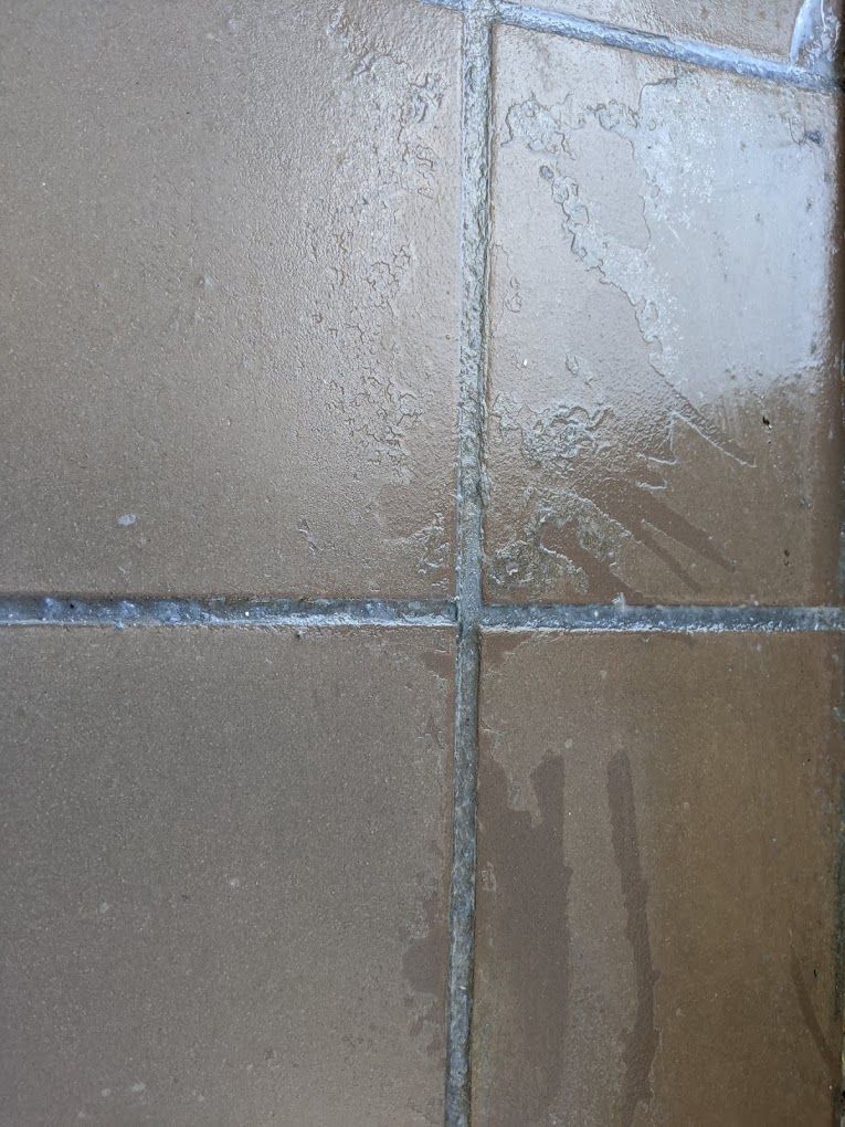 A close up of a tiled floor with a few spots of water on it