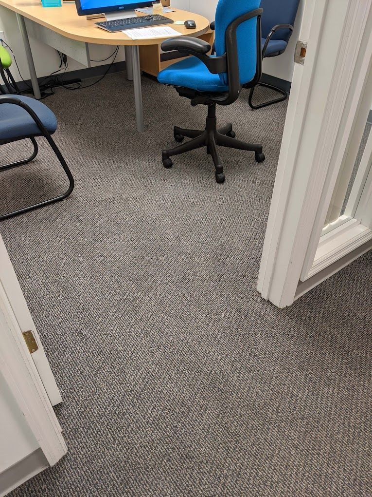 A blue office chair is sitting in front of a desk with a computer on it.