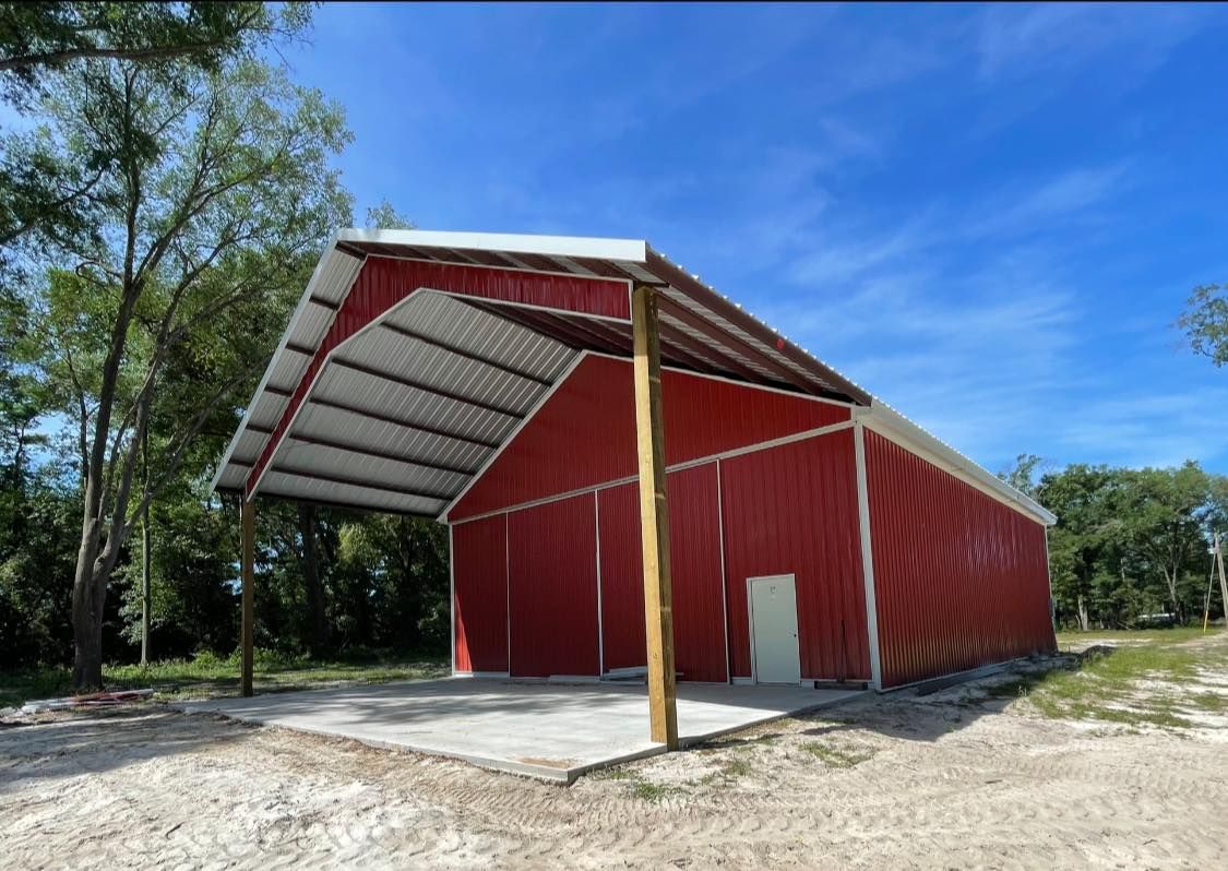 A red barn with a white roof is sitting in the middle of a dirt field.