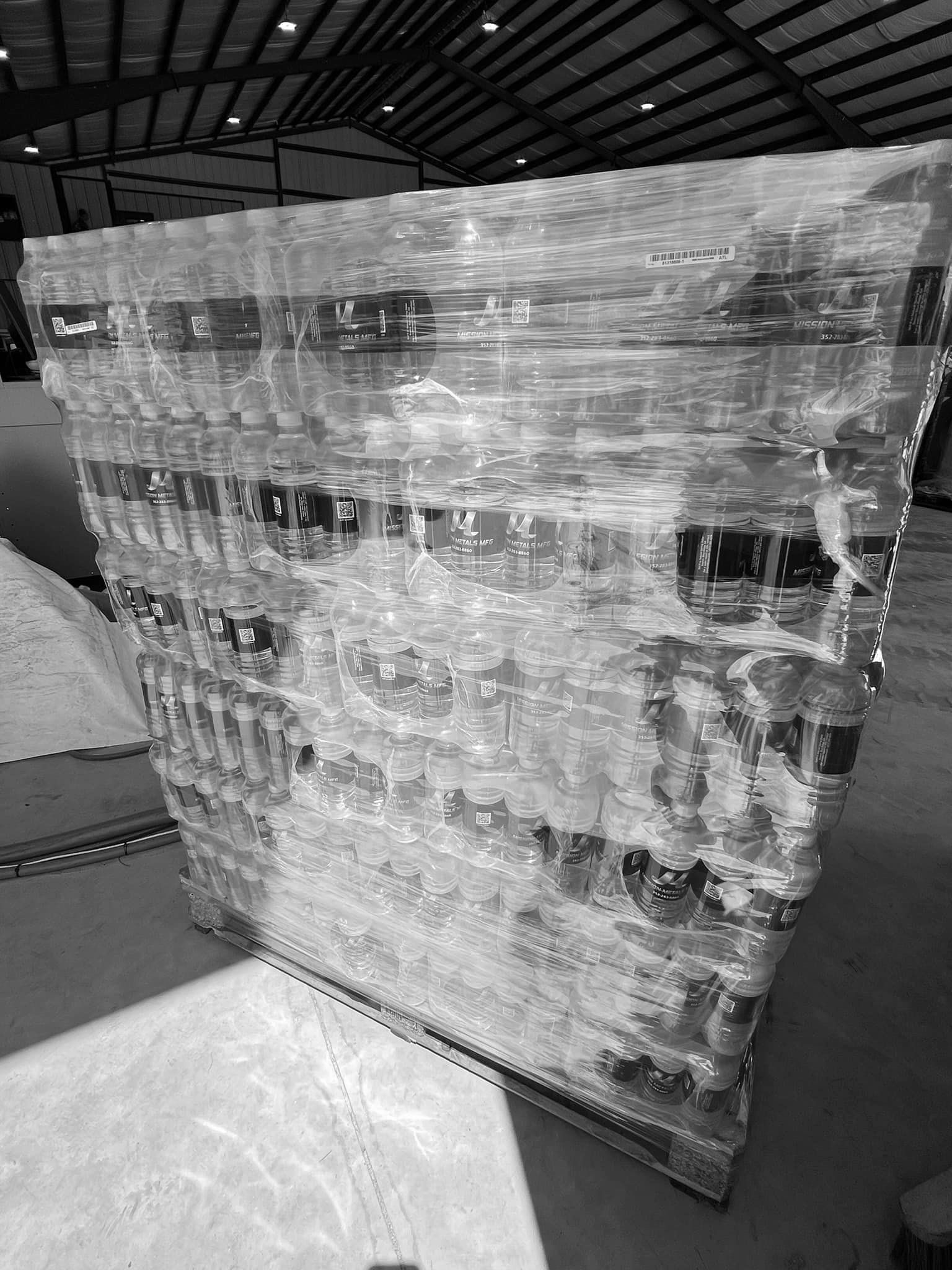 A black and white photo of a large piece of glass in a warehouse.