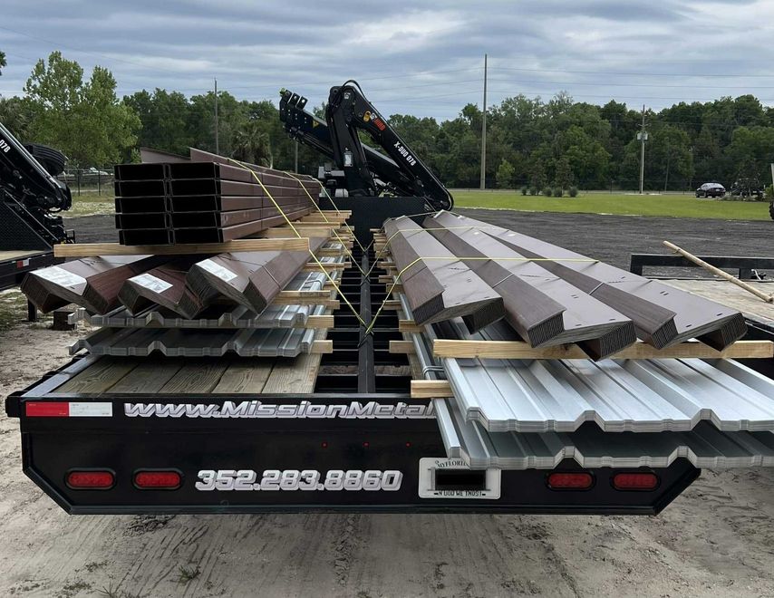 A trailer with a crane attached to it is loaded with roofing materials.