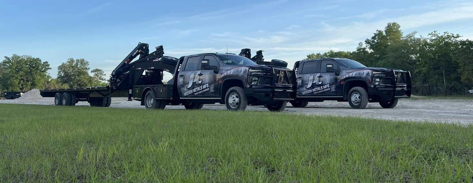 Two tow trucks are parked next to each other in a grassy field.