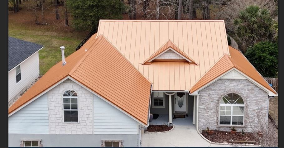 Tan roofed house with light blue siding and a brick facade. Trees in background.