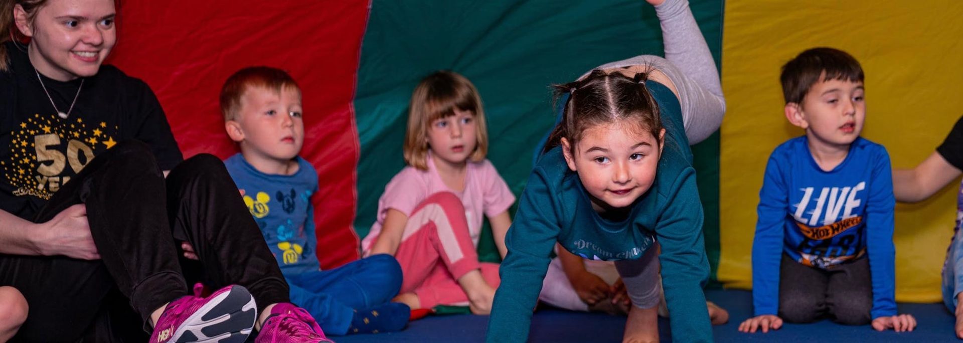 Children are sitting on the floor and doing exercises at Tumble Bees at Kids First Sports