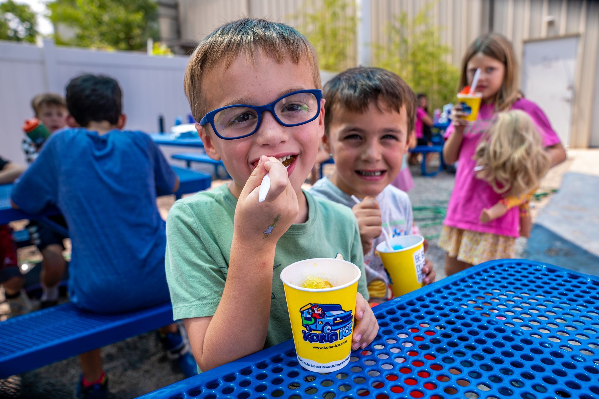 Children enjoying snow cones at Kids First Summer Camp. Two boys smile at the camera.