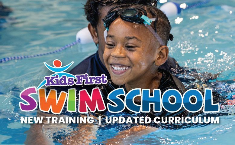 Boy smiling in pool during swim lesson with an instructor. 