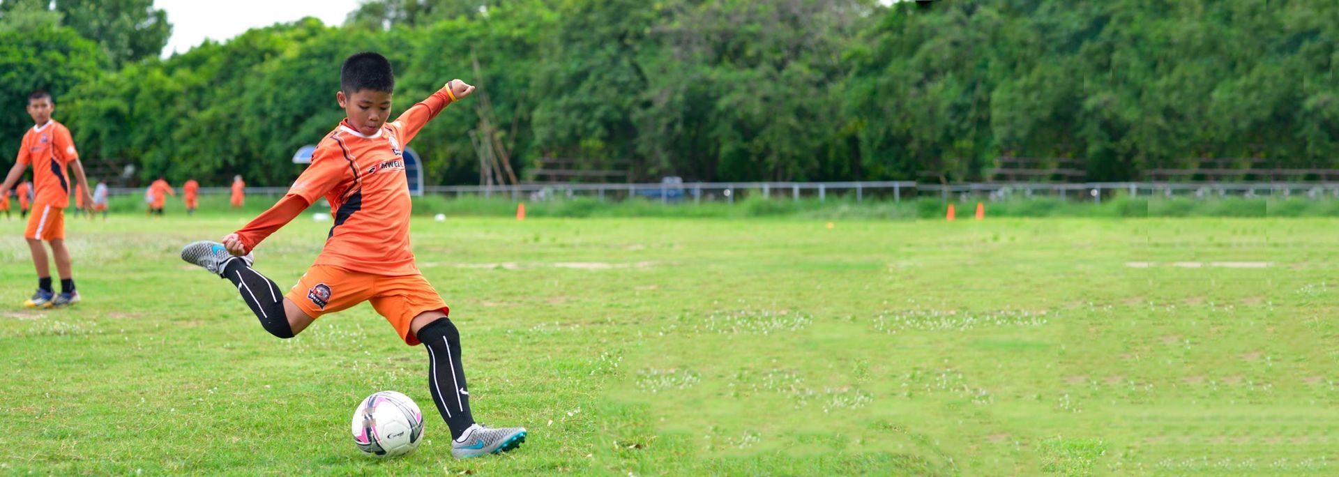 A young boy is kicking a soccer ball on a field.