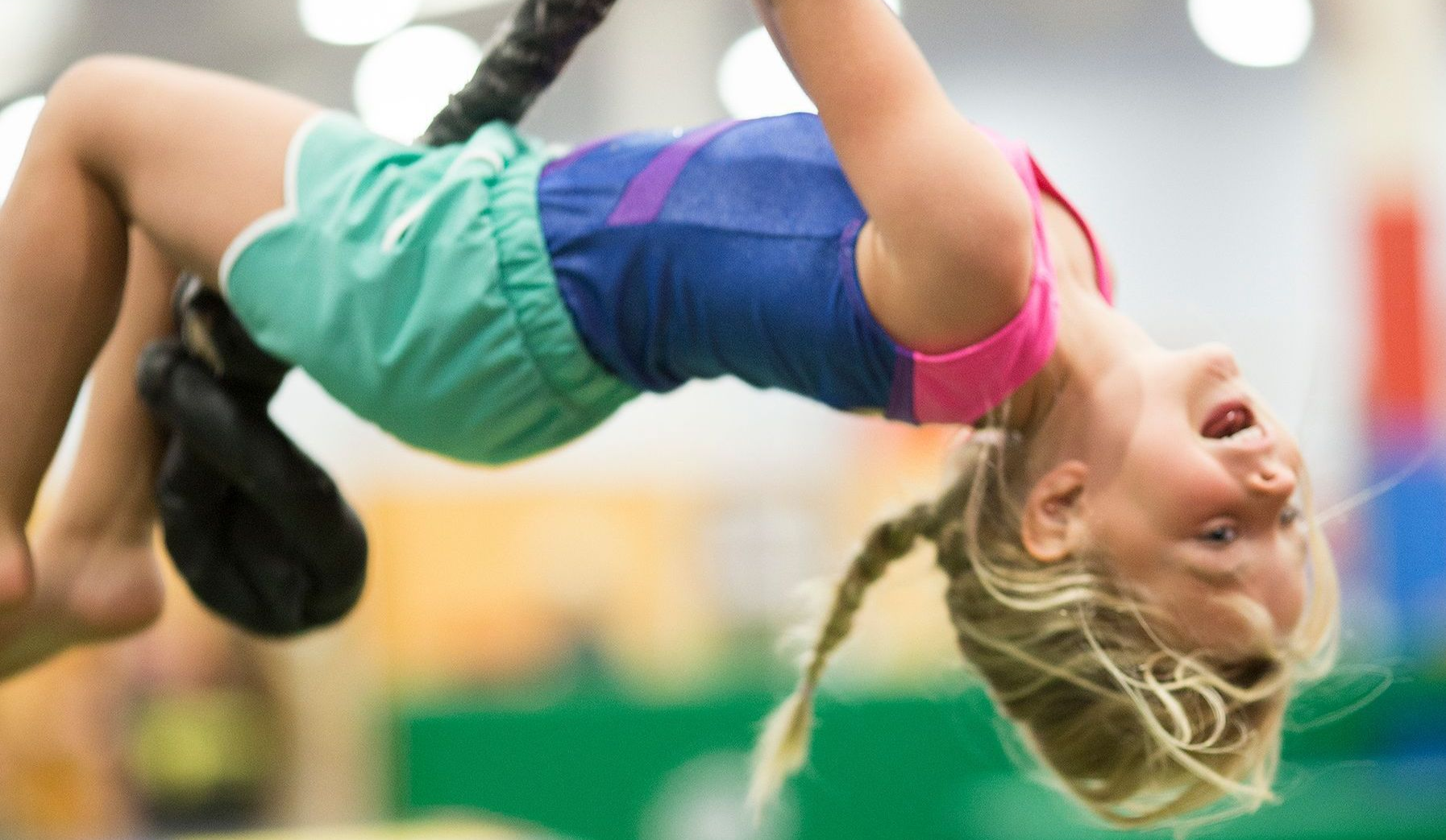 Preschool Girl swinging on a rope in a gym.