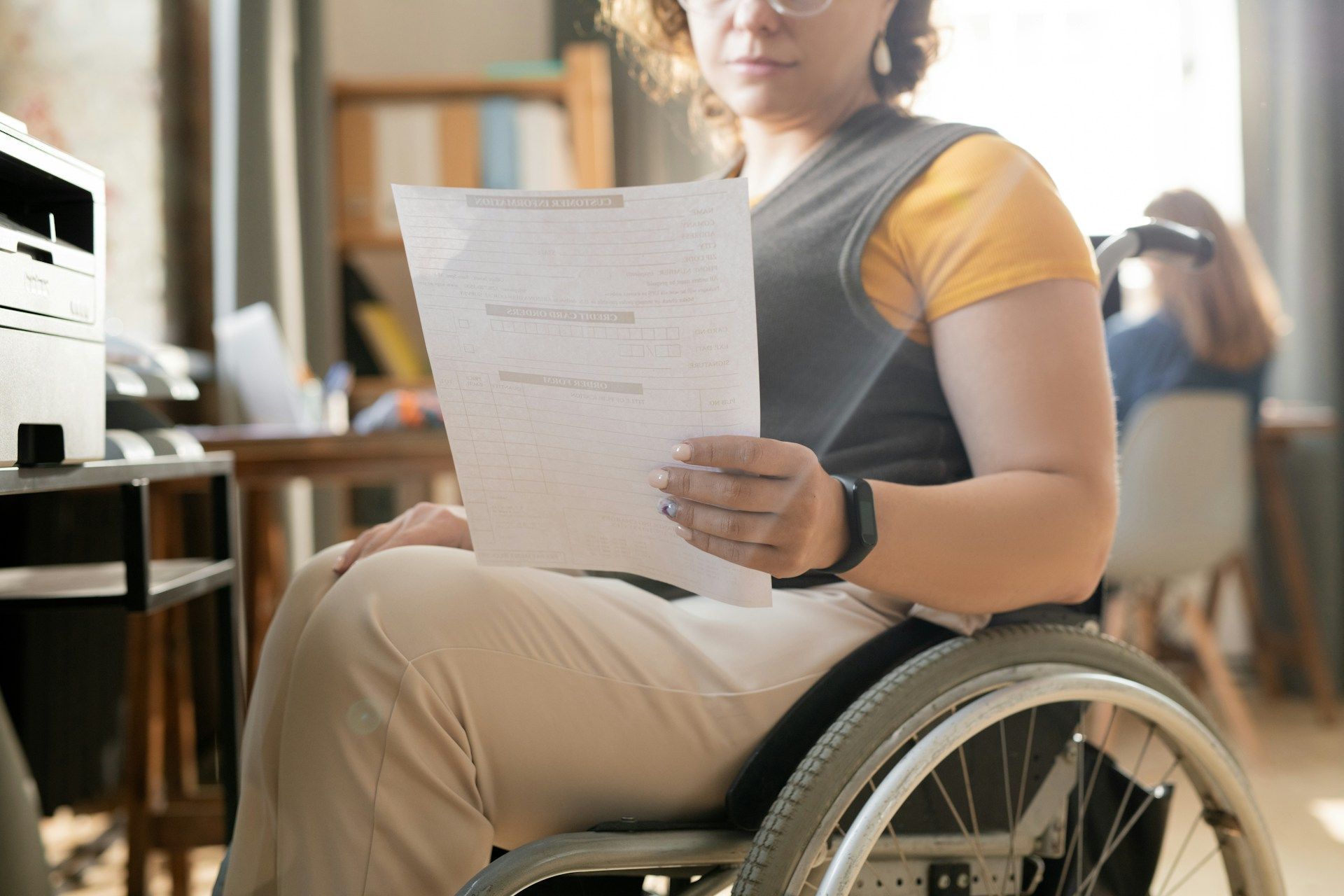 A woman in a wheelchair is holding a piece of paper.
