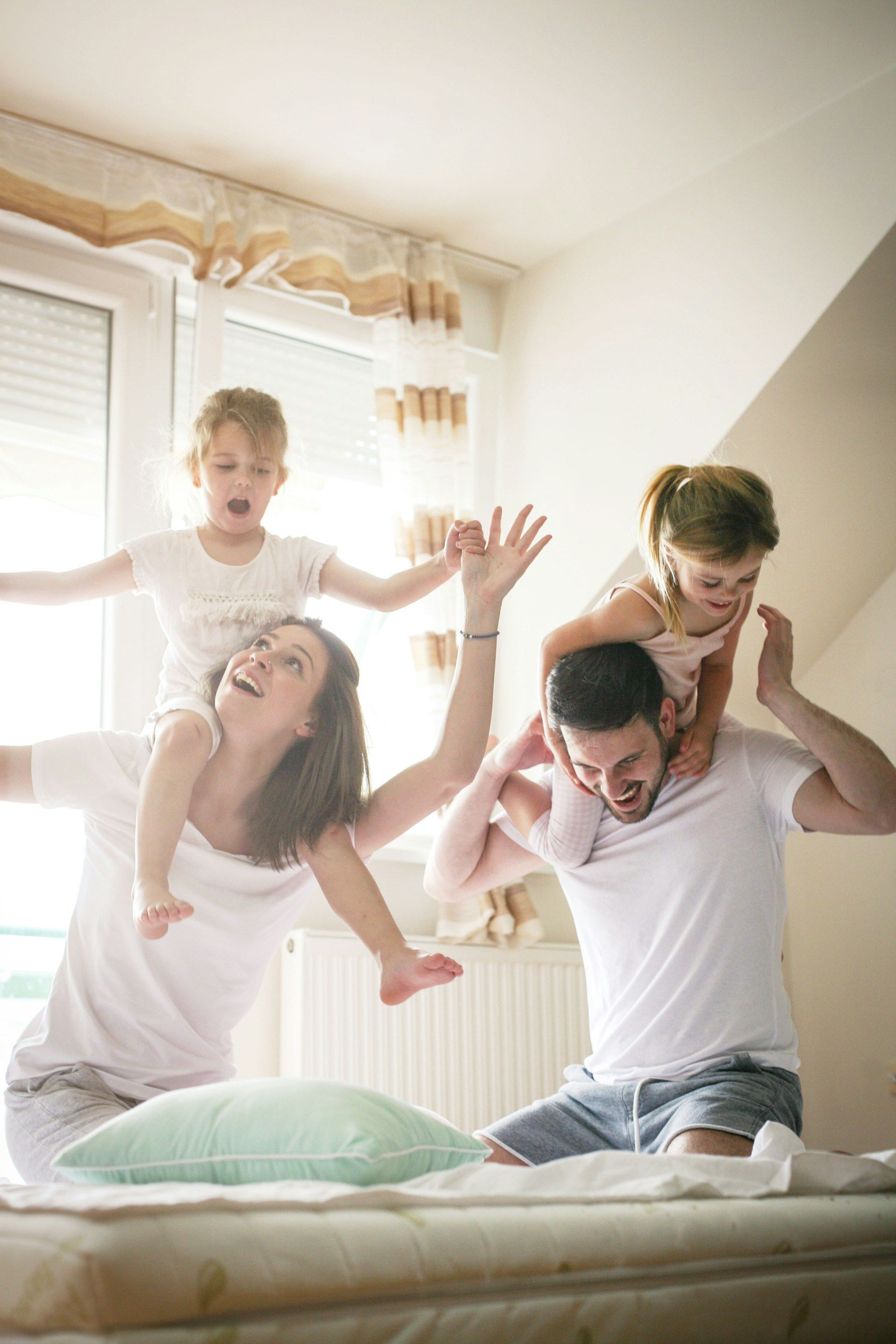 A family is sitting on a bed playing with their children.