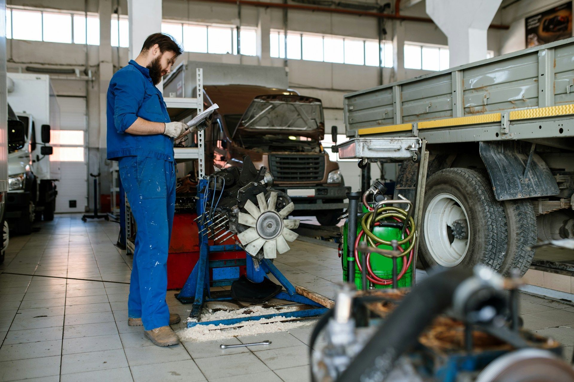 A man is working on a truck engine in a garage.