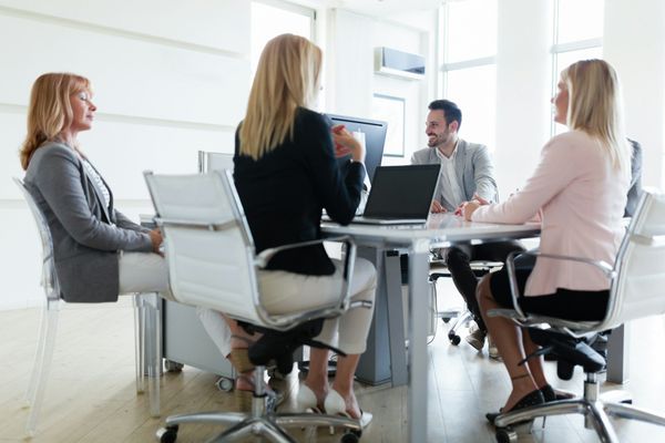 A group of people are sitting around a table with laptops.