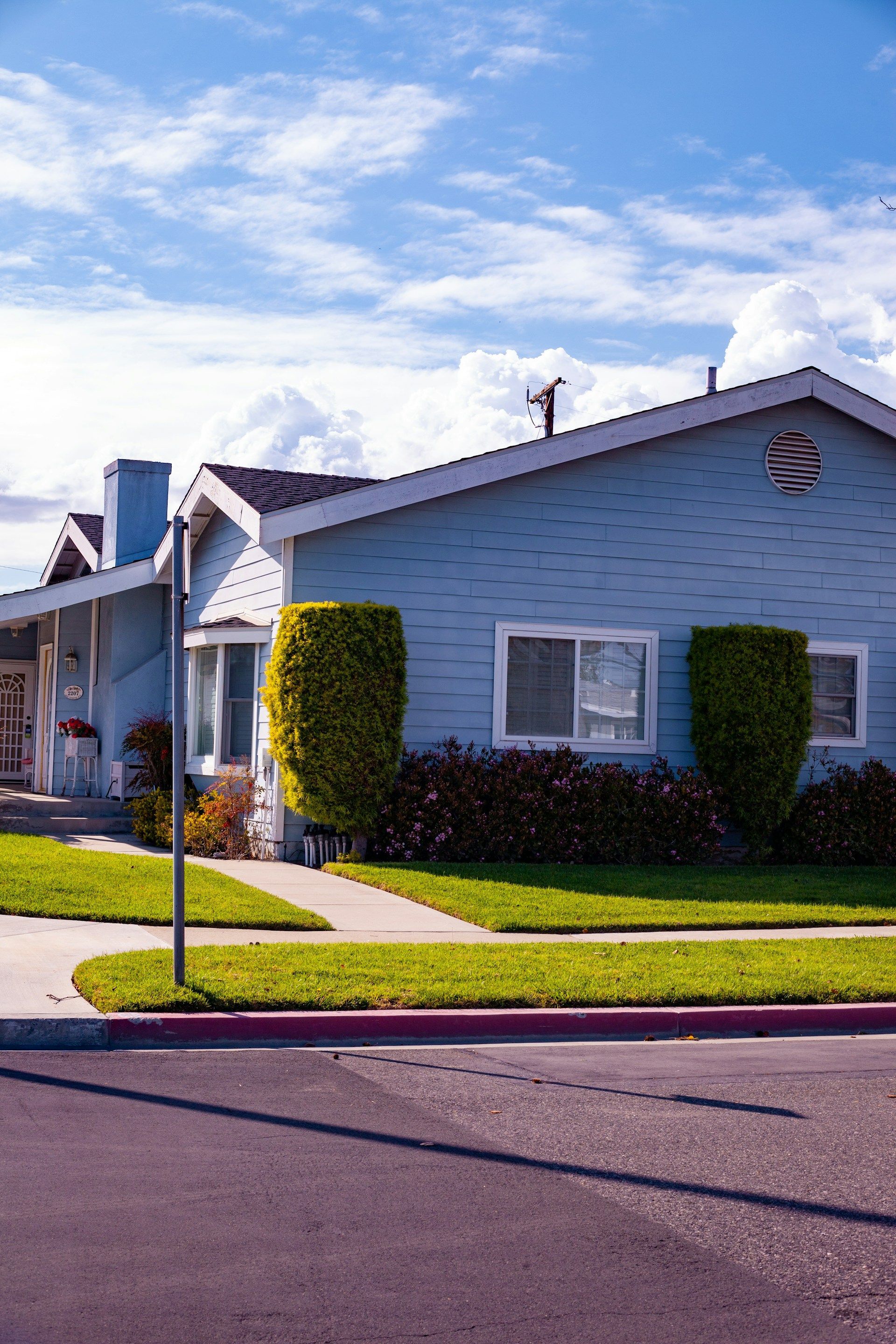 A blue house with a sign on the side of the road in front of it.