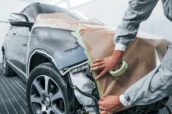 A man is painting a car in a garage.