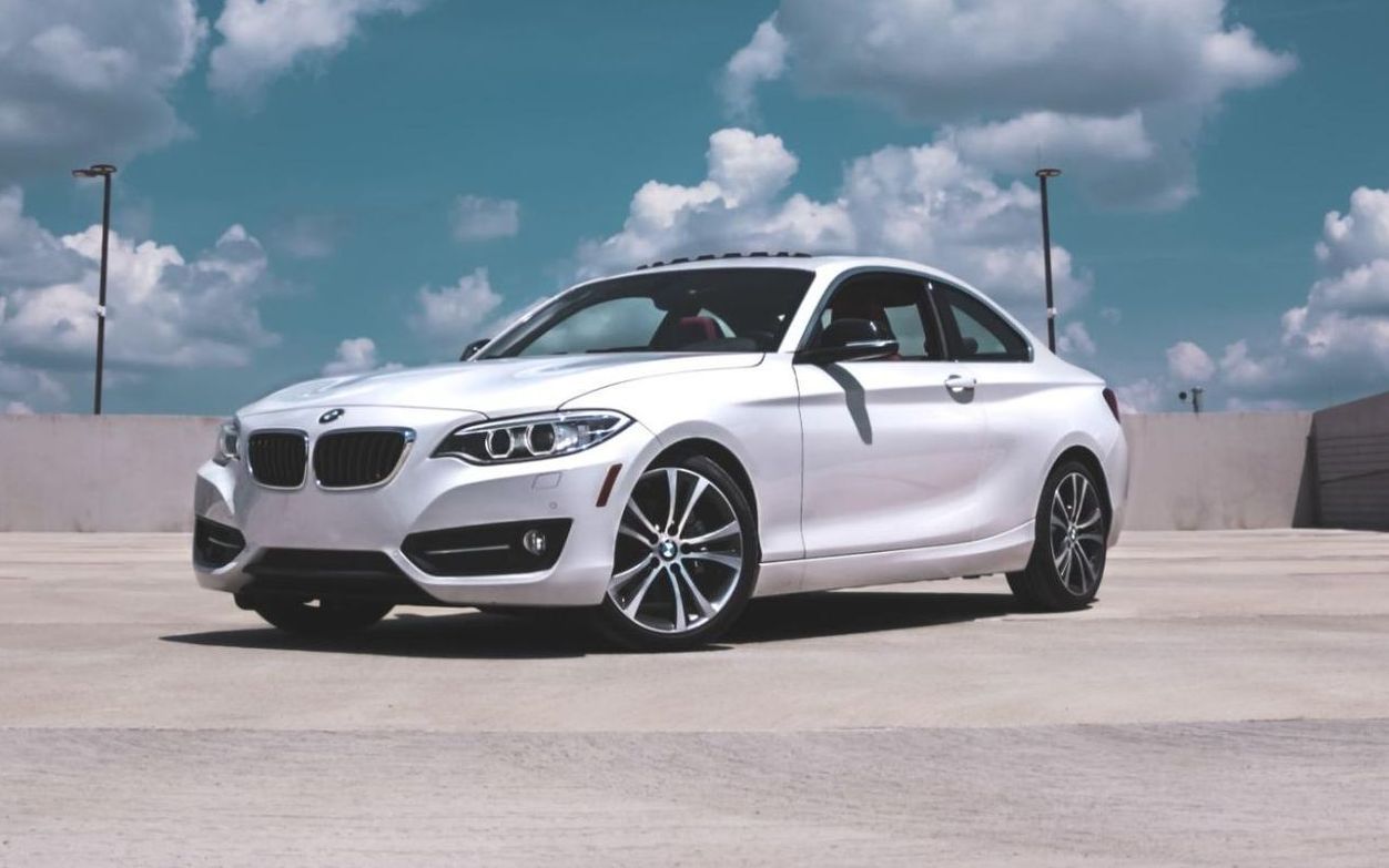 A white bmw is parked in a parking lot.