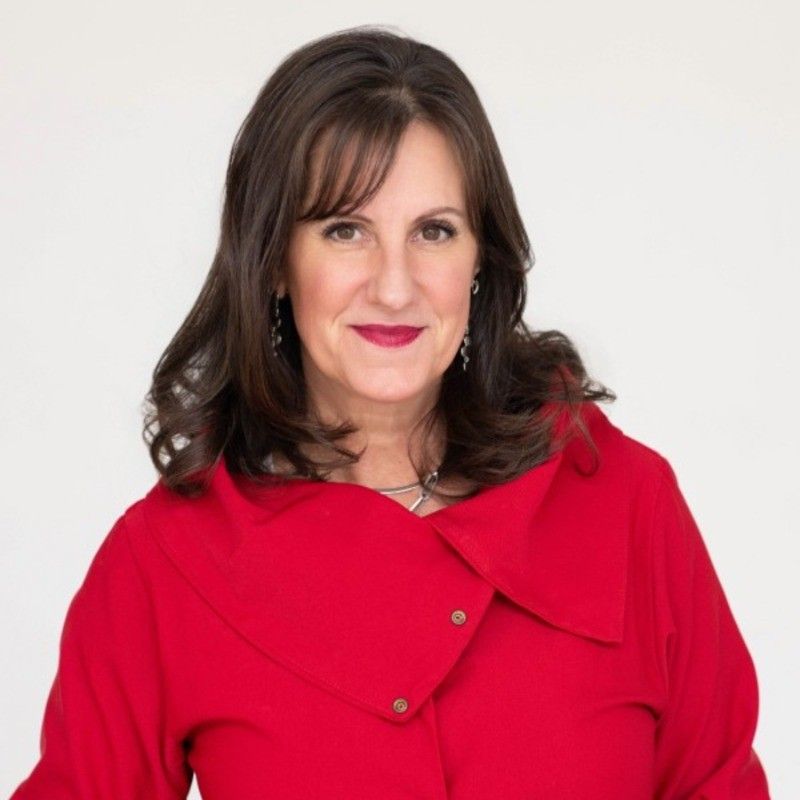 A woman in a pink dress is blowing a kiss while holding a microphone.