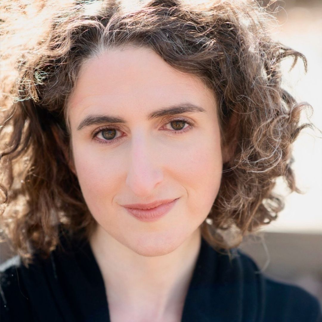 A close up of a woman 's face with curly hair.