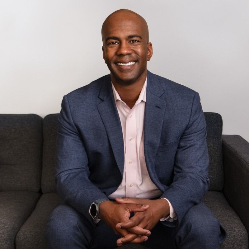 A man wearing a black shirt that says `` be great '' is giving a thumbs up.