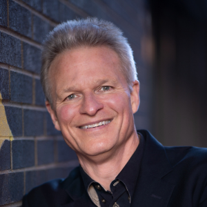 A woman in a pink dress is blowing a kiss while holding a microphone.