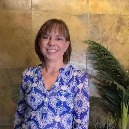 A woman in a pink dress is blowing a kiss while holding a microphone.