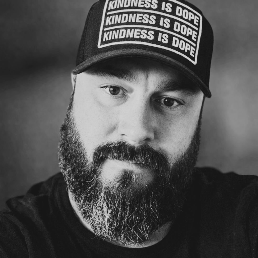 A man with dreadlocks and a beard is smiling for the camera.