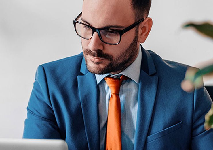 A man in a suit and tie is using a laptop computer.