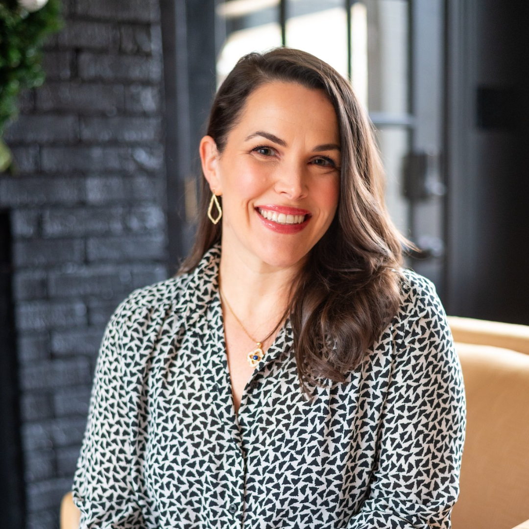 A woman is sitting in a chair and smiling for the camera.