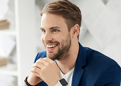 A man with a beard is smiling and wearing a smart watch.