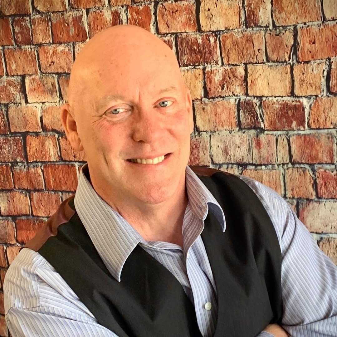 A woman in a pink dress is blowing a kiss while holding a microphone.