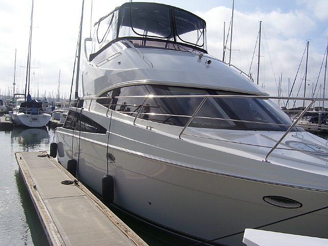 White motor yacht docked at a marina, sunny day.