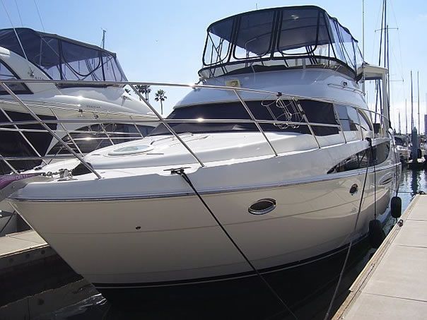 White motor yacht docked at a marina, with dark windows and a black canopy.