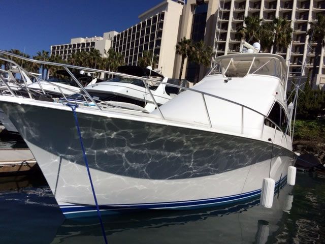 A boat is docked in a marina with a hotel in the background